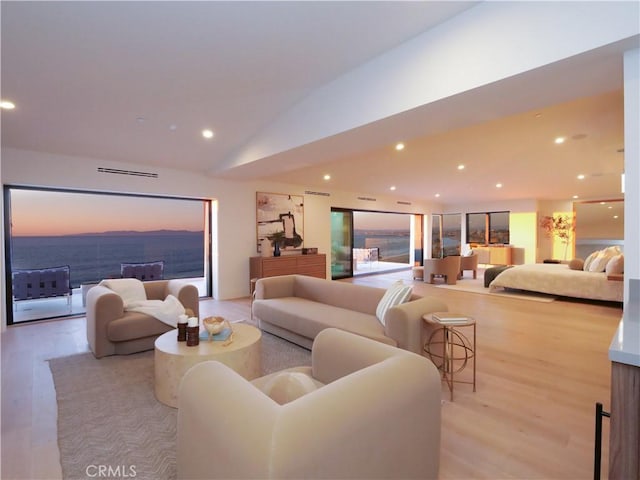 living room with light wood-type flooring, vaulted ceiling, and a water view