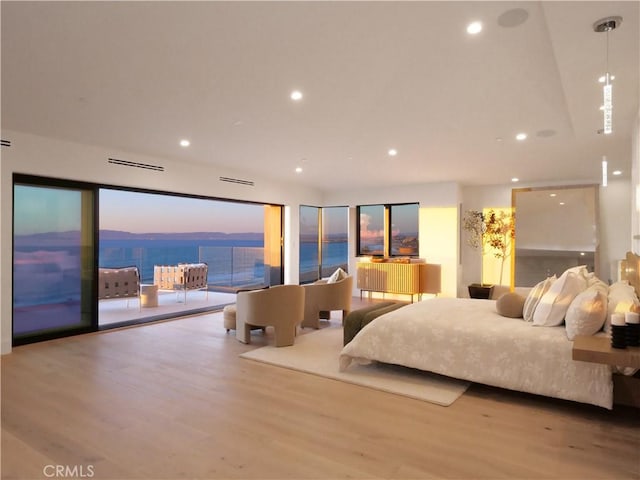 bedroom with a water view, light wood-type flooring, and access to outside