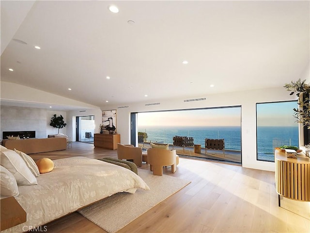 bedroom with a water view, a fireplace, access to exterior, and light wood-type flooring