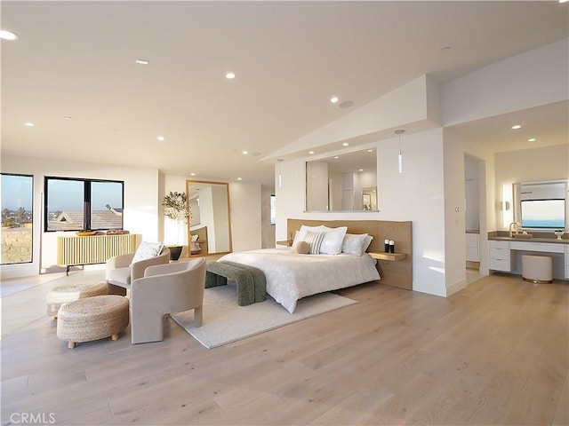 bedroom featuring lofted ceiling, sink, and light hardwood / wood-style flooring