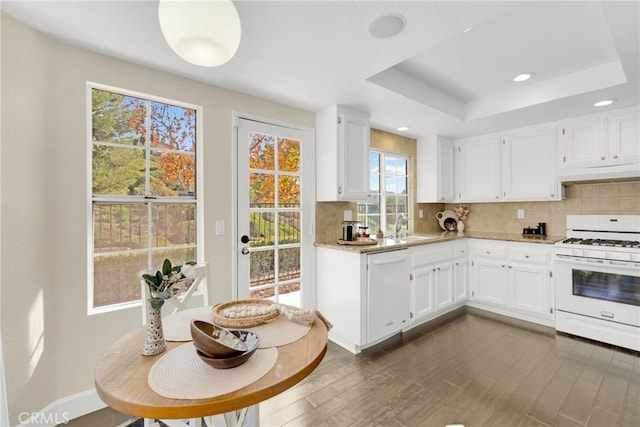 kitchen with a raised ceiling, white appliances, and white cabinetry