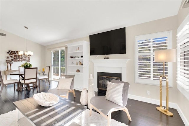 living room with dark wood-type flooring, an inviting chandelier, plenty of natural light, and lofted ceiling