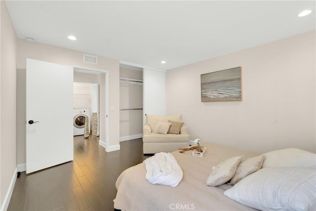 bedroom featuring washer / dryer, dark wood-type flooring, and a closet