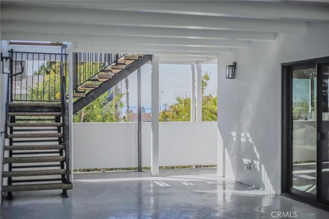 entryway with beam ceiling and concrete floors