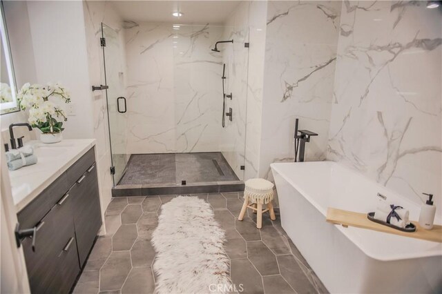 bathroom featuring tile patterned flooring, vanity, tile walls, and plus walk in shower