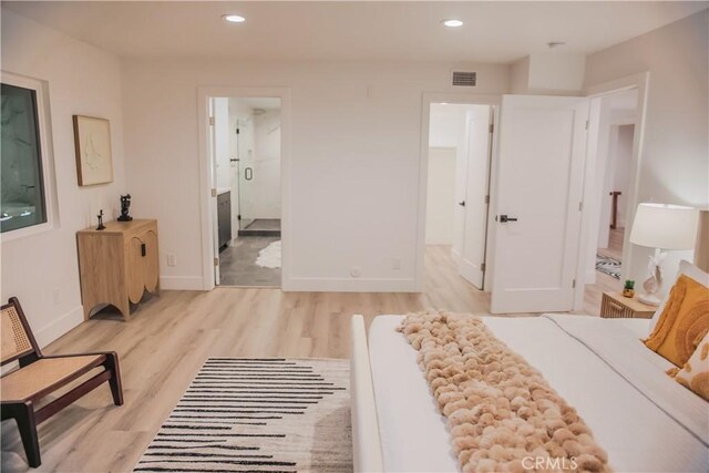 bedroom featuring ensuite bath and light wood-type flooring