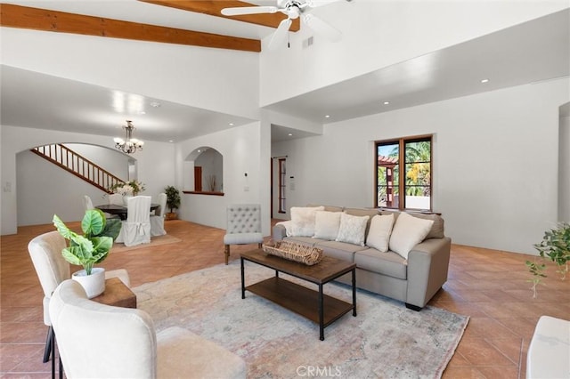 tiled living room with lofted ceiling with beams and ceiling fan with notable chandelier