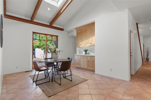 dining space featuring beam ceiling, a skylight, light tile patterned floors, and high vaulted ceiling