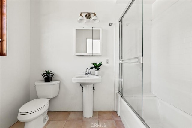 bathroom featuring shower / bath combination with glass door, tile patterned floors, and toilet