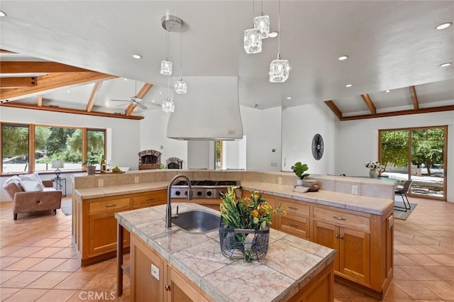 kitchen with a wealth of natural light, lofted ceiling with beams, ceiling fan, and a spacious island