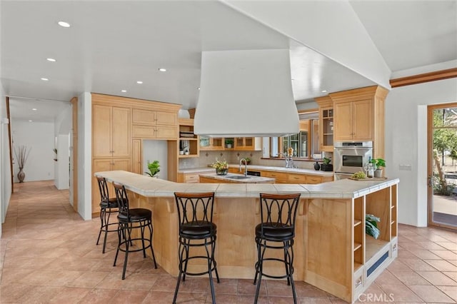 kitchen featuring kitchen peninsula, a breakfast bar, lofted ceiling, and light brown cabinets