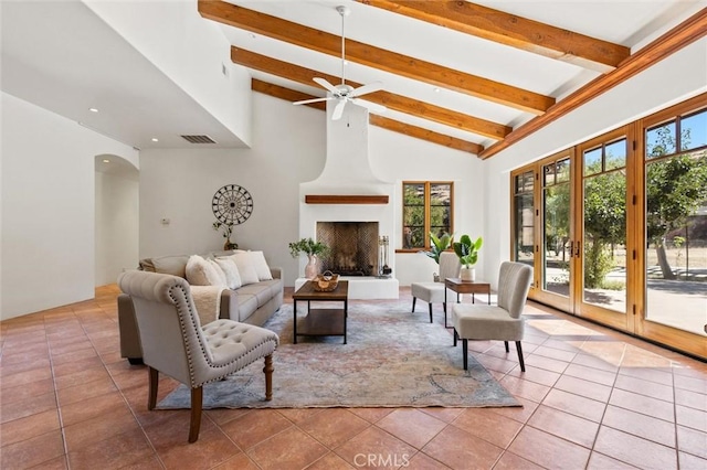 tiled living room featuring beamed ceiling, high vaulted ceiling, ceiling fan, and a fireplace