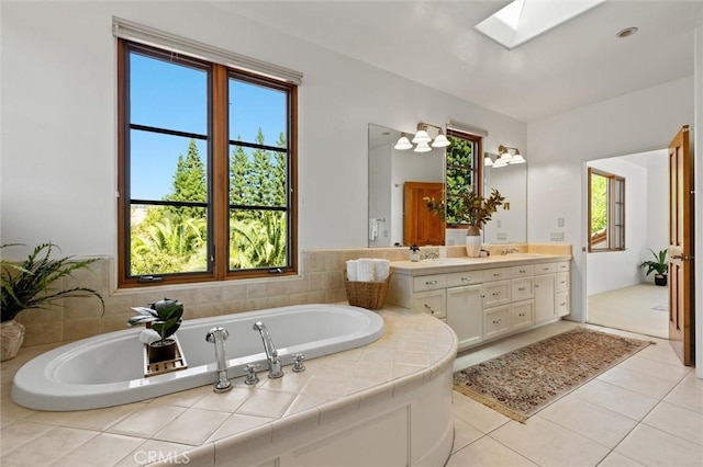 bathroom featuring tiled bath, vanity, a skylight, and a healthy amount of sunlight