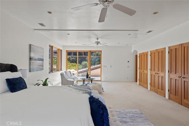 carpeted bedroom featuring ceiling fan and two closets