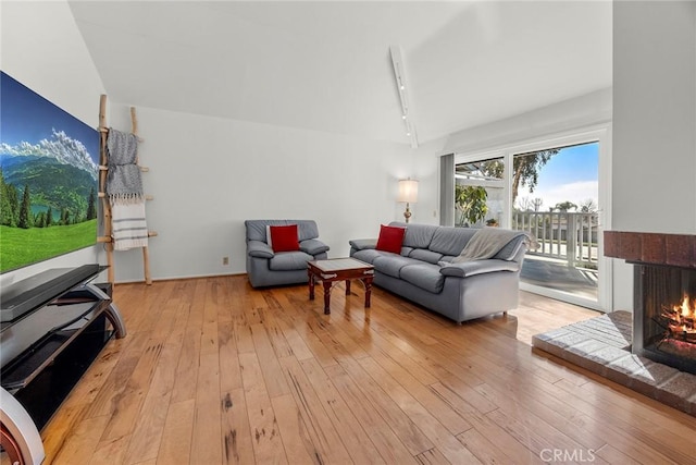 living room with a tile fireplace, light wood-type flooring, and track lighting