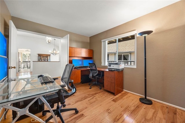 office space featuring light wood-type flooring and an inviting chandelier