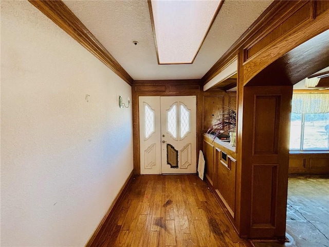 doorway featuring hardwood / wood-style flooring, a textured ceiling, and ornamental molding