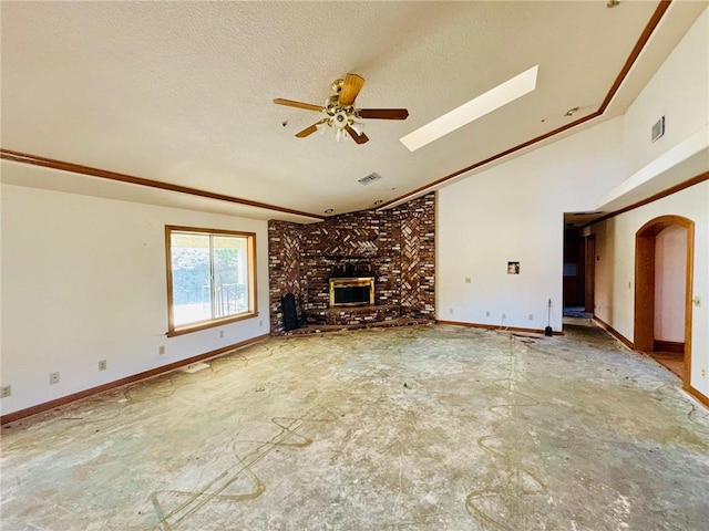 unfurnished living room featuring ceiling fan, lofted ceiling with skylight, a textured ceiling, and a wood stove