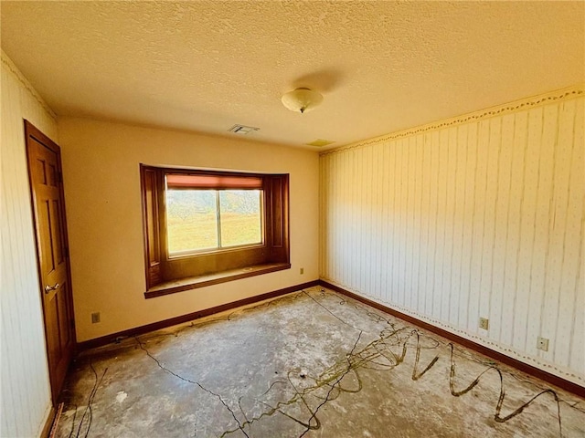 empty room with wooden walls and a textured ceiling