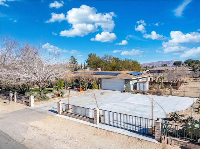 view of front of property with a garage, a mountain view, and solar panels