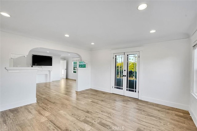 unfurnished living room with crown molding, french doors, and light wood-type flooring