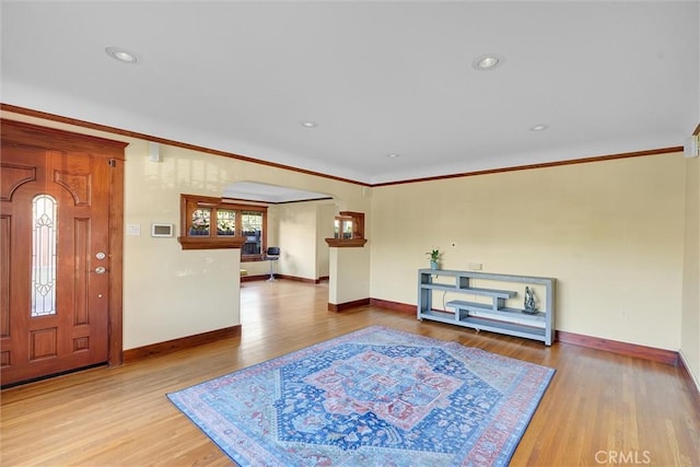 entryway with ornamental molding and hardwood / wood-style floors