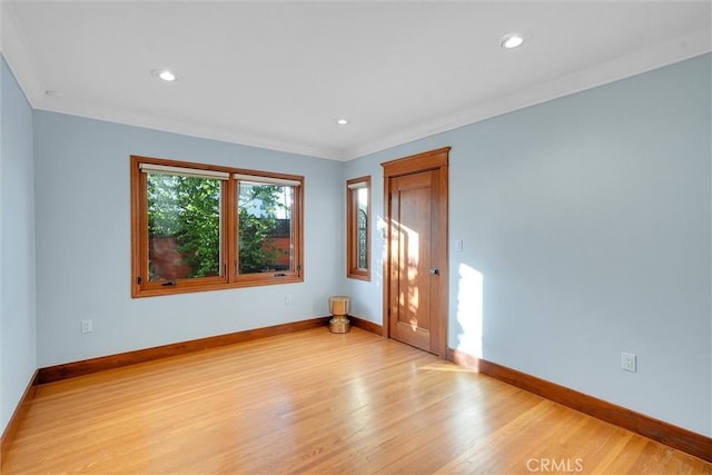 spare room with ornamental molding and light hardwood / wood-style flooring