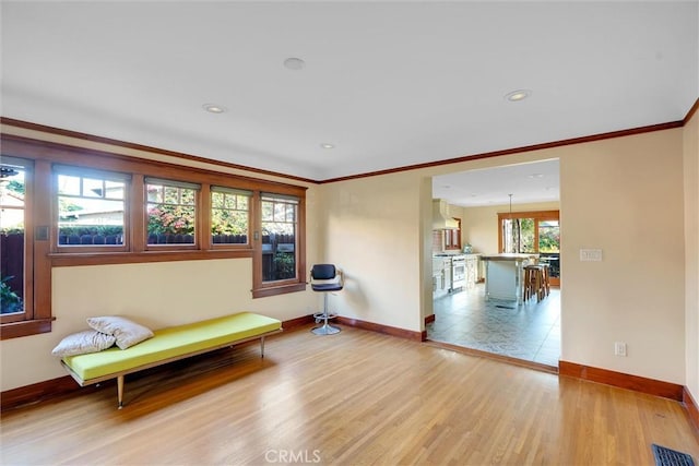 sitting room featuring light wood-type flooring and ornamental molding