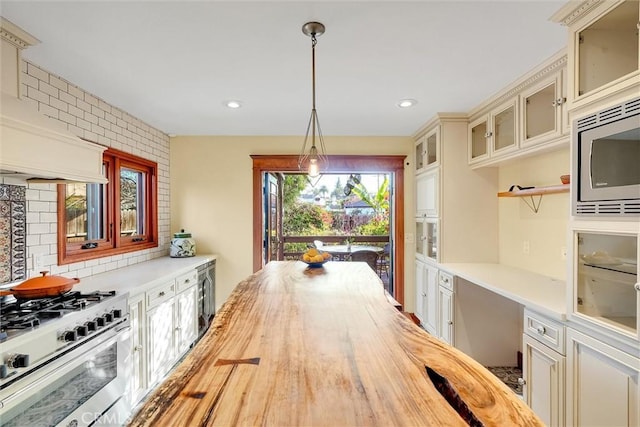 kitchen featuring hanging light fixtures, wood counters, range with gas stovetop, and tasteful backsplash