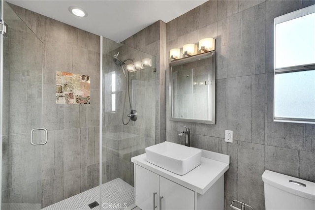 bathroom featuring toilet, vanity, and a shower with shower door