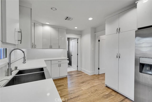 kitchen featuring white cabinetry, light hardwood / wood-style floors, stainless steel refrigerator with ice dispenser, and sink