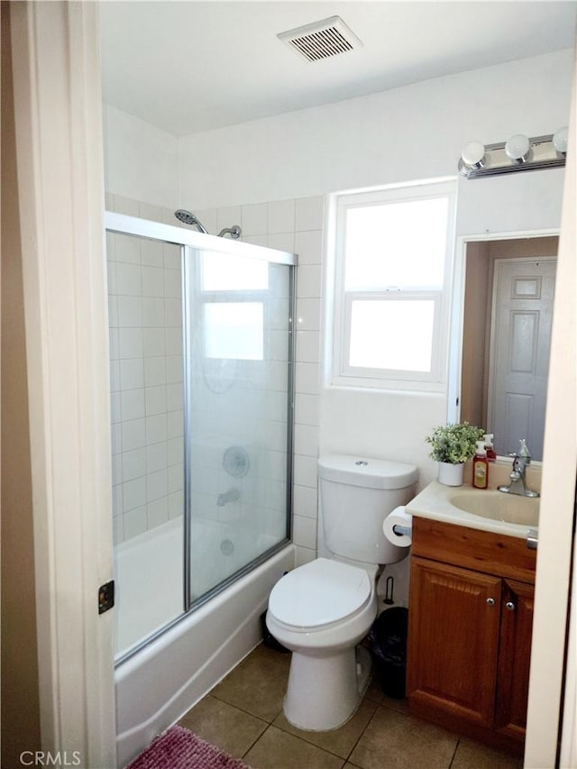 full bathroom featuring shower / bath combination with glass door, tile patterned flooring, vanity, and toilet