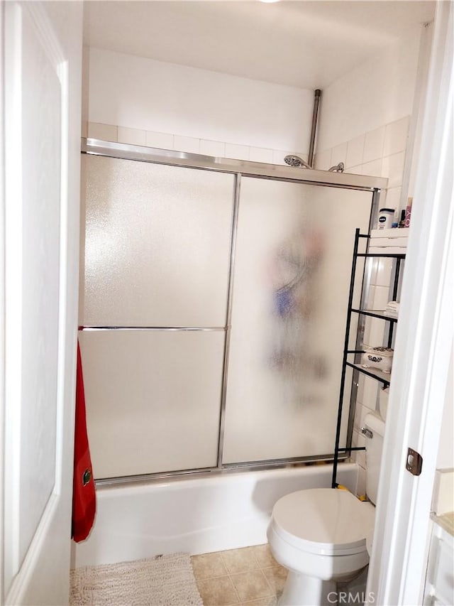 bathroom with toilet and combined bath / shower with glass door