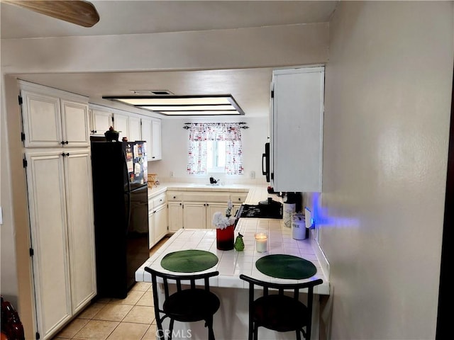 11608 Valley View Ave Unit 6, Whittier, CA 90604 - kitchen featuring light tile patterned flooring, tile countertops, white cabinets, a sink, and black appliances