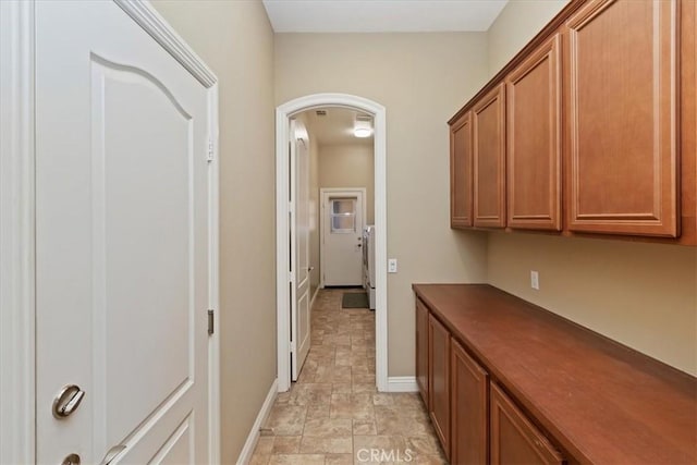 corridor with baseboards, arched walkways, and stone finish floor