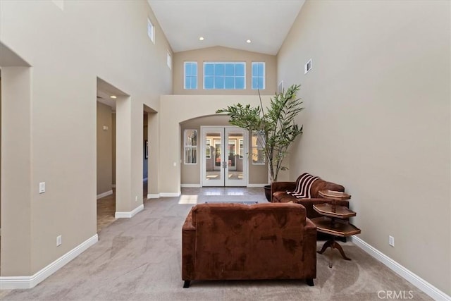 living area featuring arched walkways, french doors, baseboards, and carpet