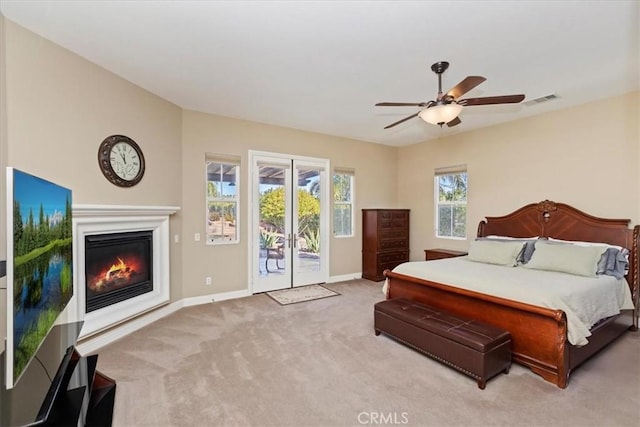 carpeted bedroom with visible vents, ceiling fan, baseboards, a glass covered fireplace, and access to outside