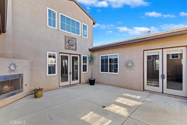 rear view of property featuring a patio area, french doors, and stucco siding