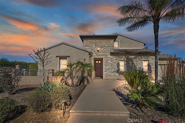 view of front facade with stone siding, stucco siding, and fence