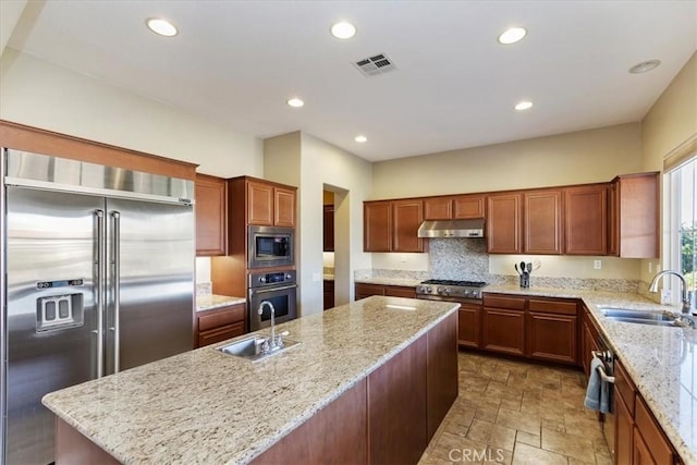 kitchen with under cabinet range hood, built in appliances, visible vents, and a sink