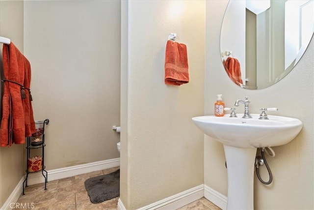 bathroom featuring a sink, baseboards, and toilet