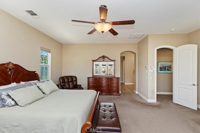 bedroom with light carpet, visible vents, arched walkways, and baseboards