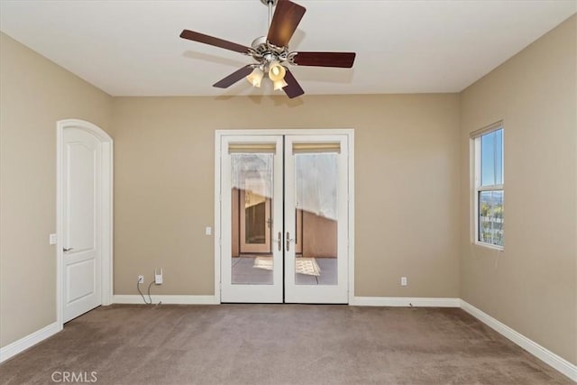 carpeted spare room with a ceiling fan, baseboards, and french doors