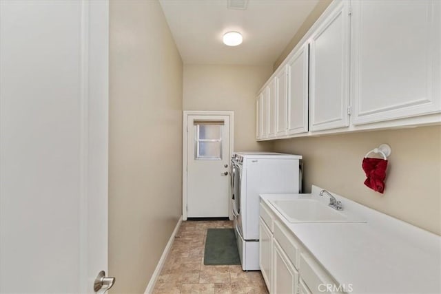 washroom with washing machine and clothes dryer, cabinet space, baseboards, and a sink