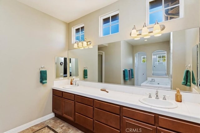 bathroom with double vanity, baseboards, a sink, and a bath