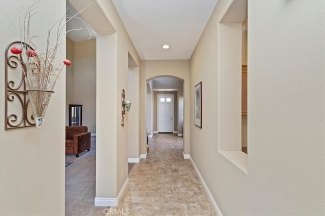 hallway with arched walkways and baseboards