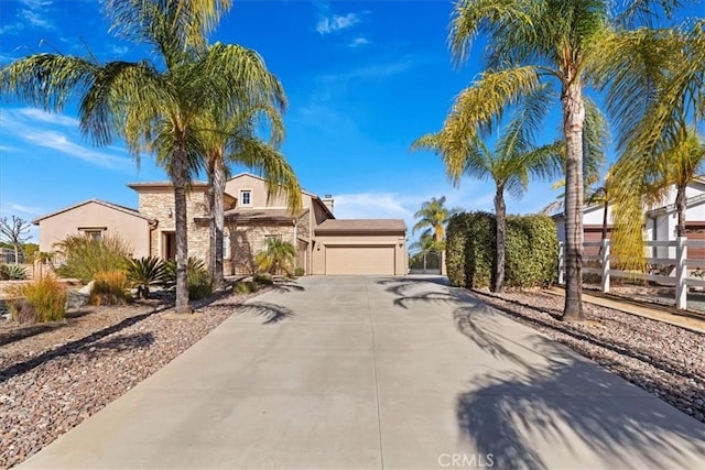 view of front of house featuring fence, an attached garage, stucco siding, concrete driveway, and stone siding