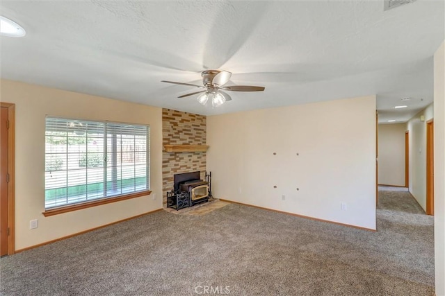 unfurnished living room featuring carpet, a wood stove, and ceiling fan