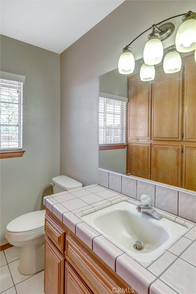 bathroom featuring toilet, vanity, tile patterned floors, and a healthy amount of sunlight