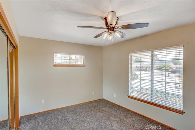 carpeted spare room featuring ceiling fan